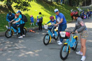 Familias preparando bicicletas en un parque.