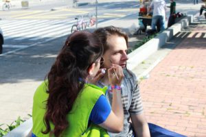 Mujer pinta la cara de un hombre en la calle.